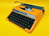 Front-side view of a vibrant Electric Orange Silver Reed 100 manual typewriter in its original black hardshell case.