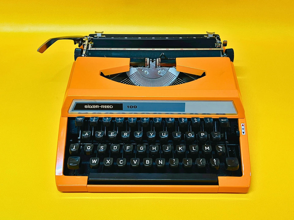 Detailed shot of the AZERTY keyboard on an orange Silver Reed 100, featuring crisp white keys and French accents