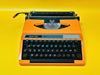 Detailed shot of the AZERTY keyboard on an orange Silver Reed 100, featuring crisp white keys and French accents