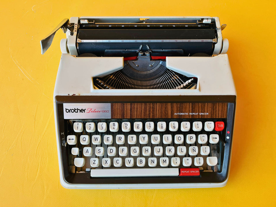 Close-up shot of the Automatic Repeat Spacer key on a Brother Deluxe 1350, highlighting the red accent and professional dark grey keys.