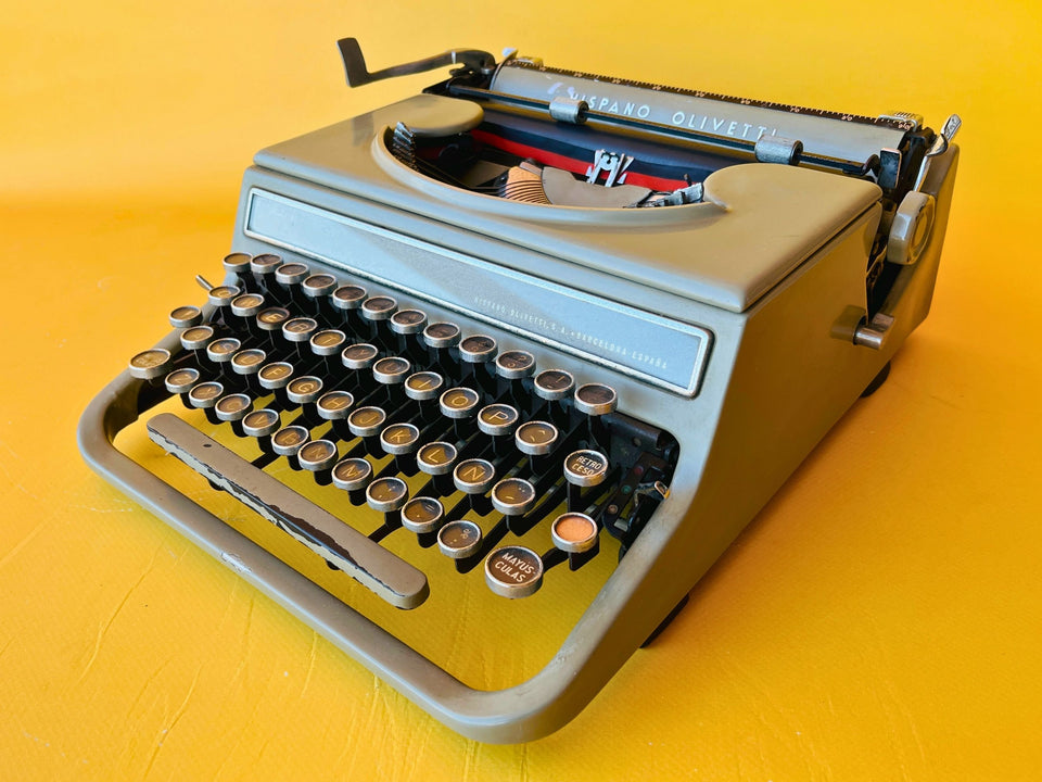 Front-side view of a 1940s Hispano Olivetti Studio 46 in sage green with rare glass keys against a yellow background.