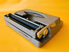 Brother Typewriter (1970s) – Gray Portable Manual Typewriter with Leather Case