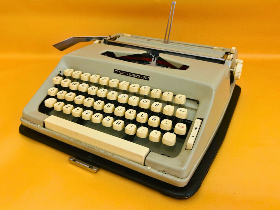 Front-side view of an Arctic White Maritsa 22 manual typewriter with cream keys against a vibrant yellow background.