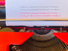 Close-up shot of a type sample sheet in the carriage rail, demonstrating perfect letter alignment and crisp, dark impressions in both black and red ink.