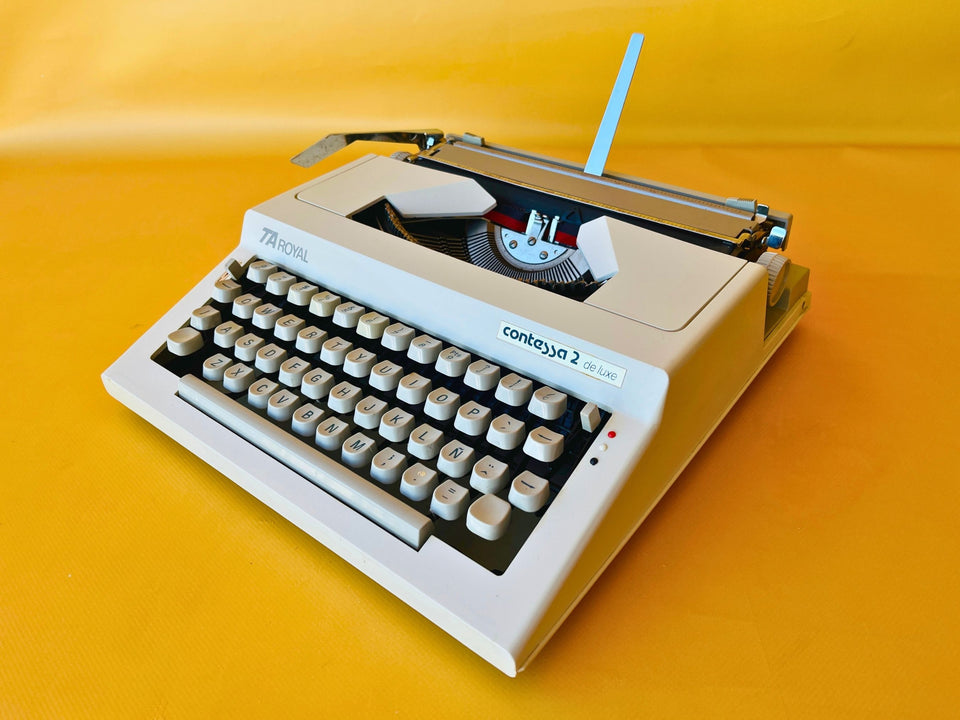 Front-three-quarter view of a pristine Arctic White Royal Contessa 2 de Luxe manual typewriter against a yellow background