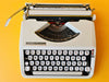 Hermes baby typewriter close keyboard shot QWERTY on yello wbackground
