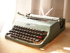 Front-side view of a classic blue-green Olivetti Lettera 32 manual typewriter in excellent condition with paper in the carriage